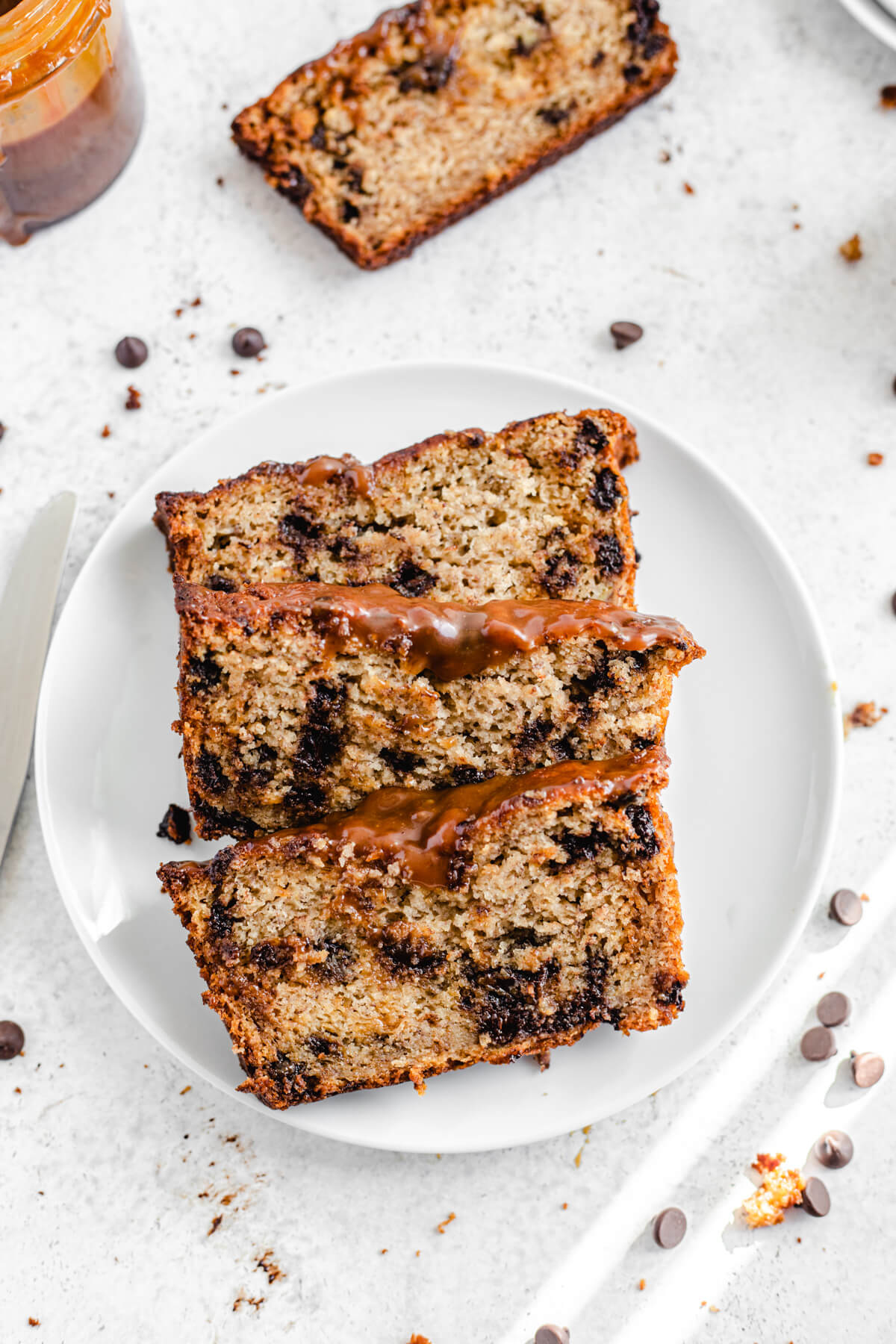 top view of three banana loaf slices on a white plate with an extra slice off to the side