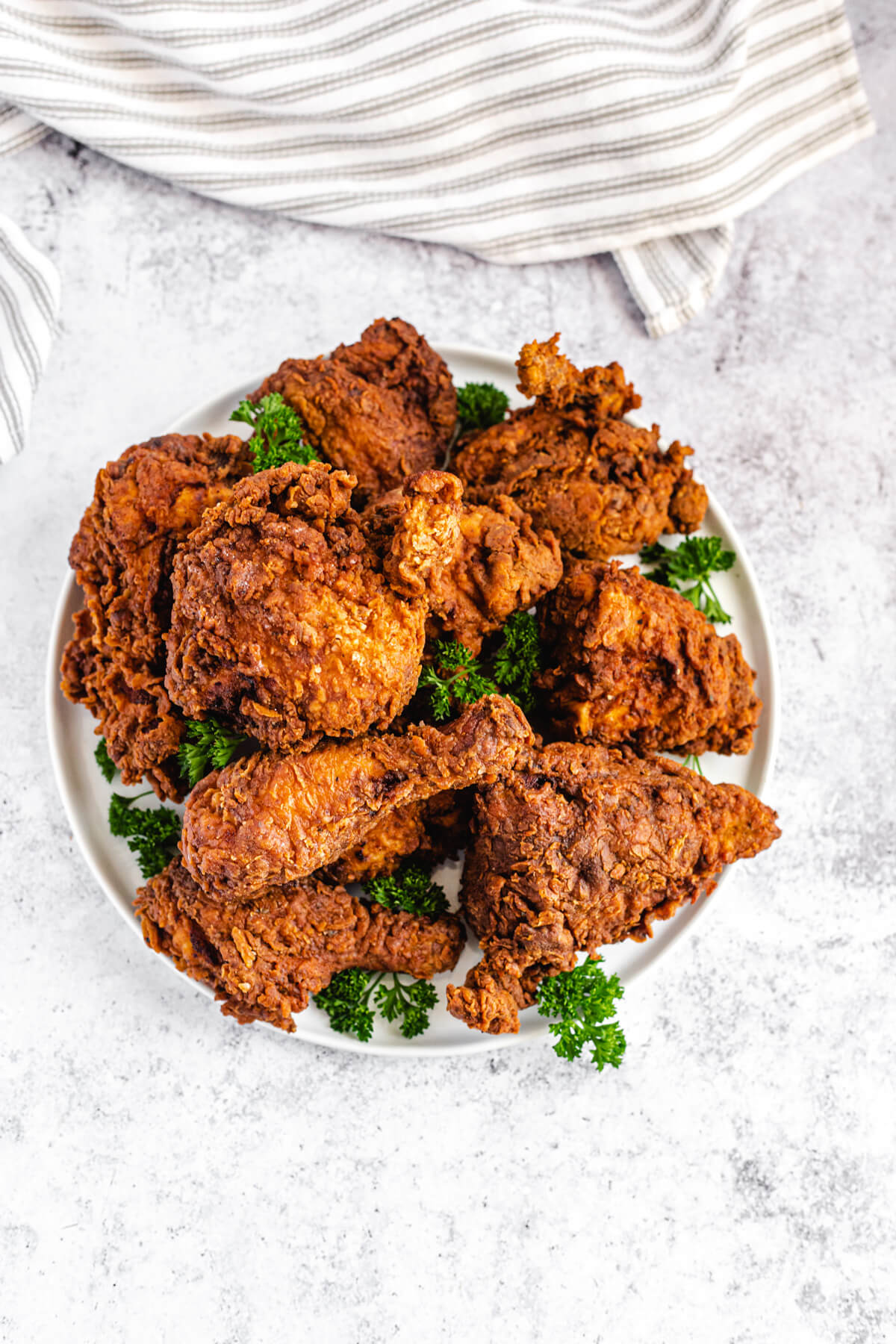 top view of chicken pieces and fresh parsley leaves on a large white plate