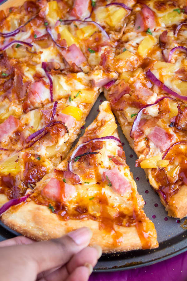 Hawaiian BBQ Pizza — Thick and chewy pizza crust topped with tangy barbecue sauce, ham, pineapple, bacon, red onions and loads of cheese. This flavourful pizza will definitely be your family's new Friday night fave!