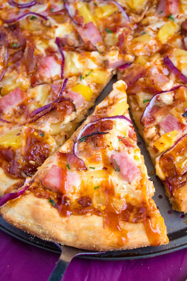 Hawaiian BBQ Pizza — Thick and chewy pizza crust topped with tangy barbecue sauce, ham, pineapple, bacon, red onions and loads of cheese. This flavourful pizza will definitely be your family's new Friday night fave!