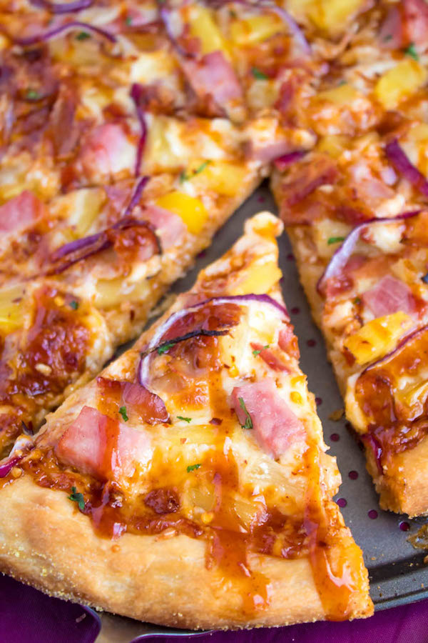Hawaiian BBQ Pizza — Thick and chewy pizza crust topped with tangy barbecue sauce, ham, pineapple, bacon, red onions and loads of cheese. This flavourful pizza will definitely be your family's new Friday night fave!