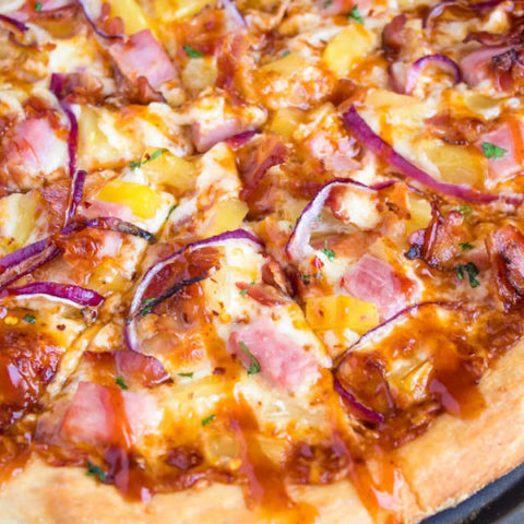 Hawaiian BBQ Pizza — Thick and chewy pizza crust topped with tangy barbecue sauce, ham, pineapple, bacon, red onions and loads of cheese. This flavourful pizza will definitely be your family's new Friday night fave!