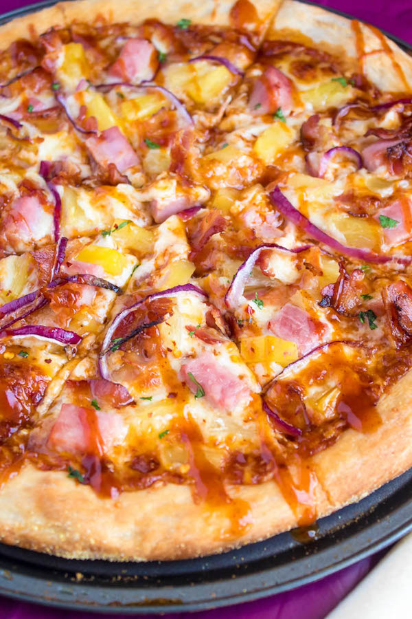 Hawaiian BBQ Pizza — Thick and chewy pizza crust topped with tangy barbecue sauce, ham, pineapple, bacon, red onions and loads of cheese. This flavourful pizza will definitely be your family's new Friday night fave!