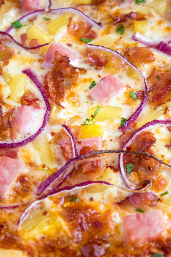 Hawaiian BBQ Pizza — Thick and chewy pizza crust topped with tangy barbecue sauce, ham, pineapple, bacon, red onions and loads of cheese. This flavourful pizza will definitely be your family's new Friday night fave!