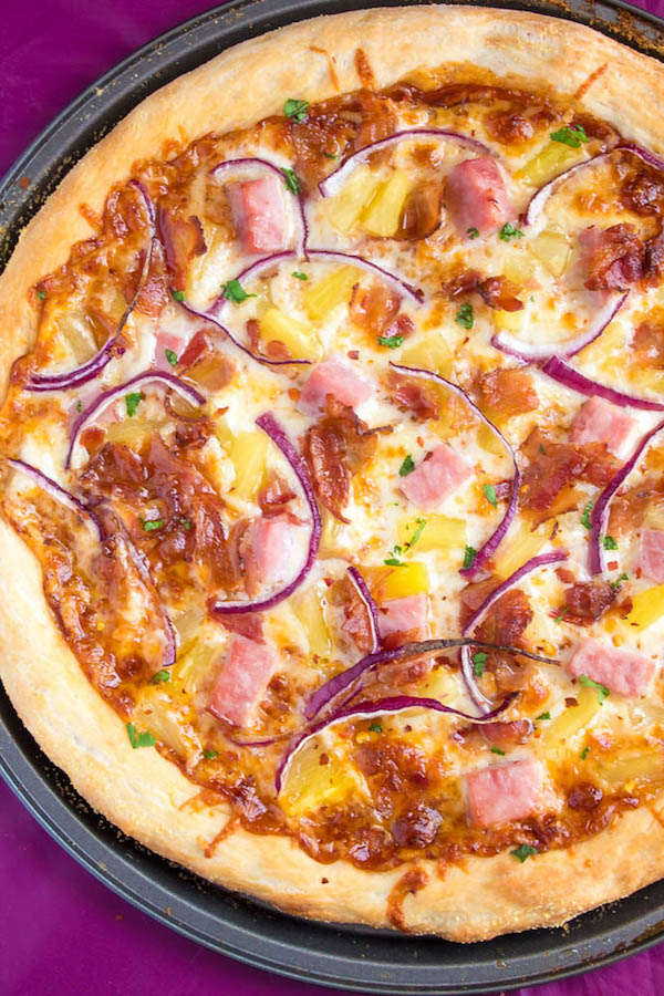 Hawaiian BBQ Pizza — Thick and chewy pizza crust topped with tangy barbecue sauce, ham, pineapple, bacon, red onions and loads of cheese. This flavourful pizza will definitely be your family's new Friday night fave!