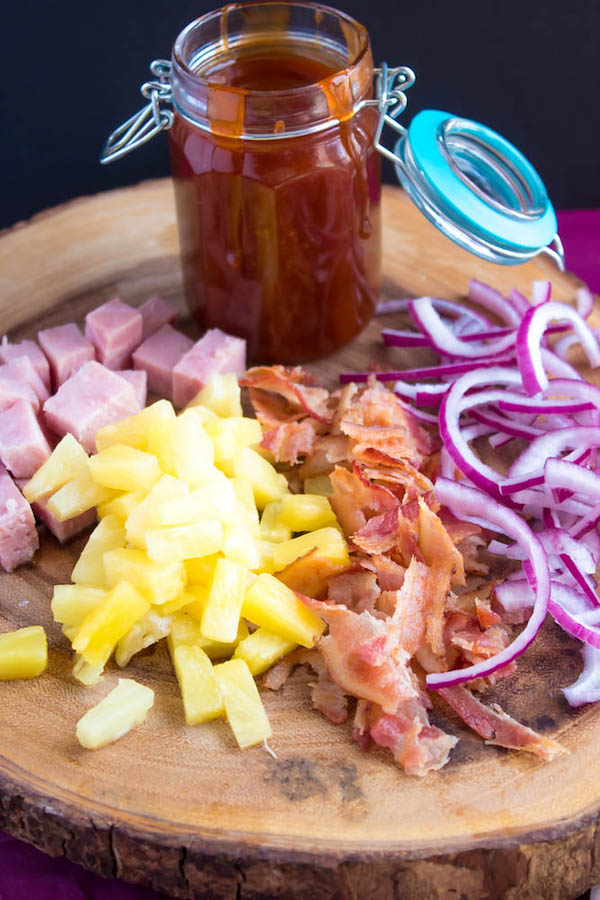 Hawaiian BBQ Pizza — Thick and chewy pizza crust topped with tangy barbecue sauce, ham, pineapple, bacon, red onions and loads of cheese. This flavourful pizza will definitely be your family's new Friday night fave!