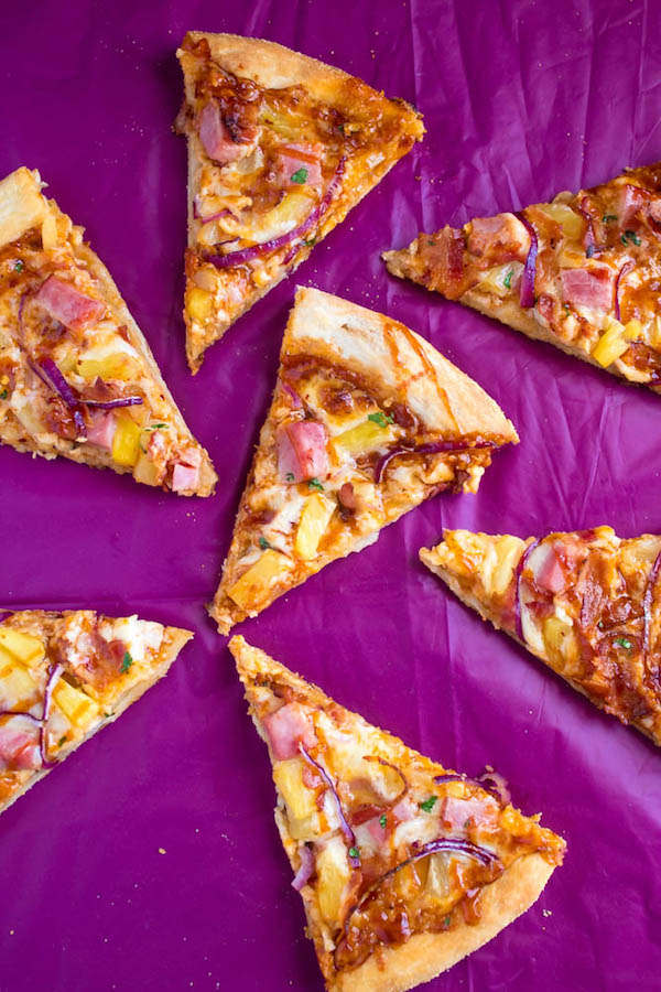 Hawaiian BBQ Pizza — Thick and chewy pizza crust topped with tangy barbecue sauce, ham, pineapple, bacon, red onions and loads of cheese. This flavourful pizza will definitely be your family's new Friday night fave!