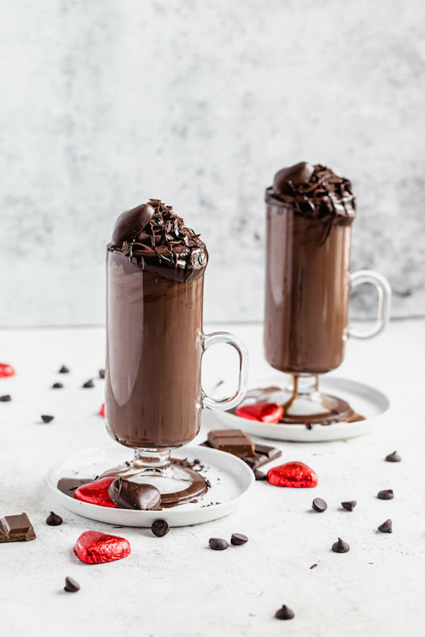 two glasses of hot chocolate on white appetizer plates