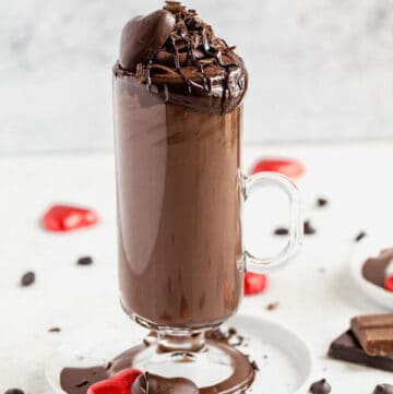 Tall glass of dark hot chocolate on a small white plate