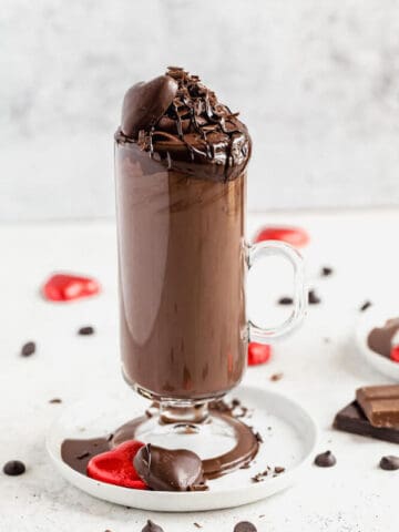 Tall glass of dark hot chocolate on a small white plate