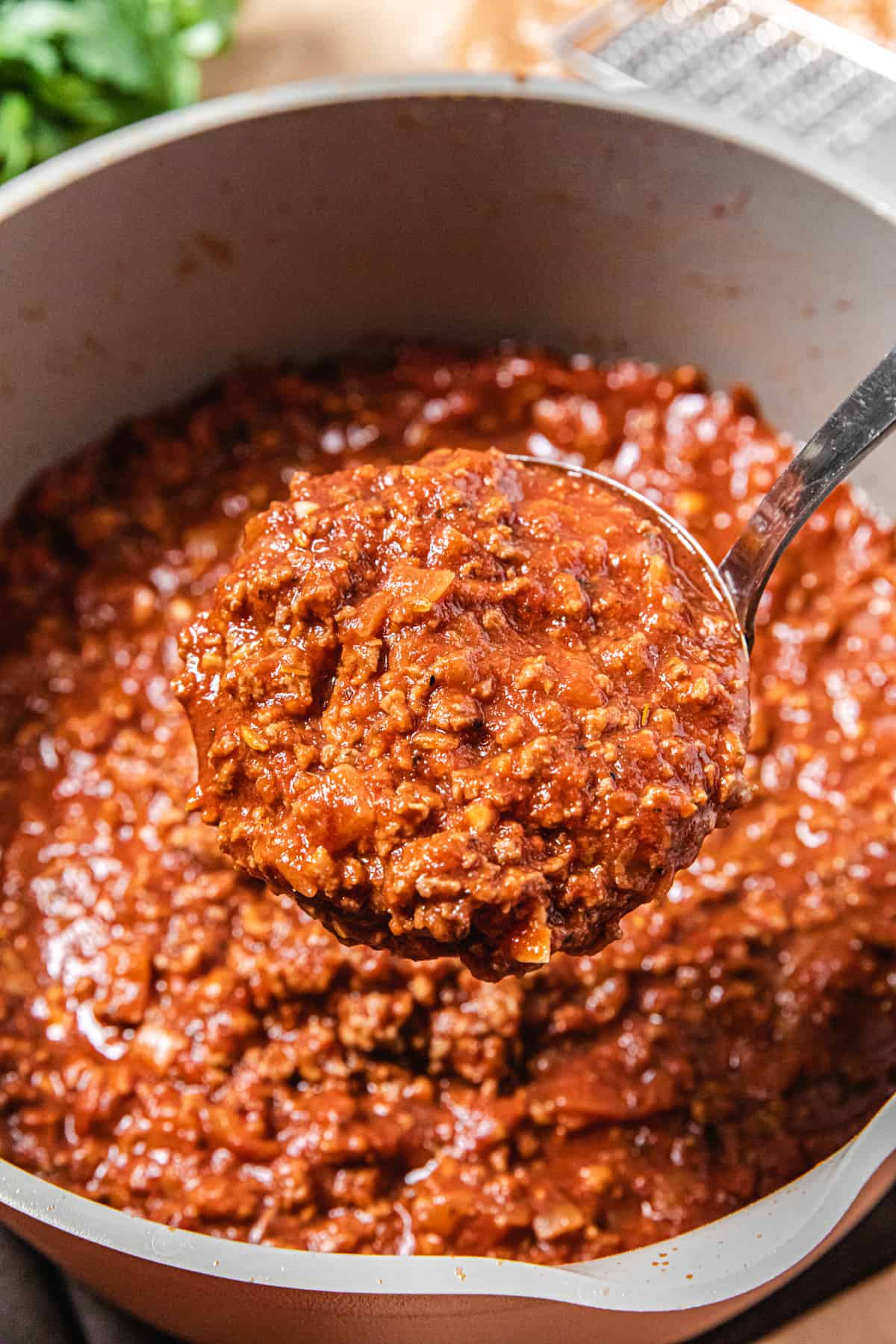 lifting a ladle of meat sauce out of a pot