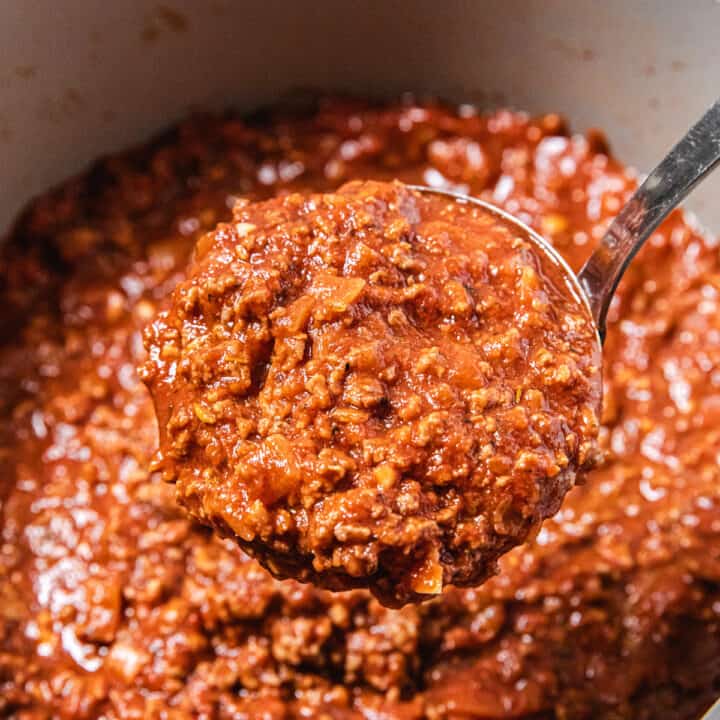 ladle of meat pasta sauce over big pot