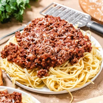 plate of spaghetti and meat sauce with fresh parmesan wedge in front