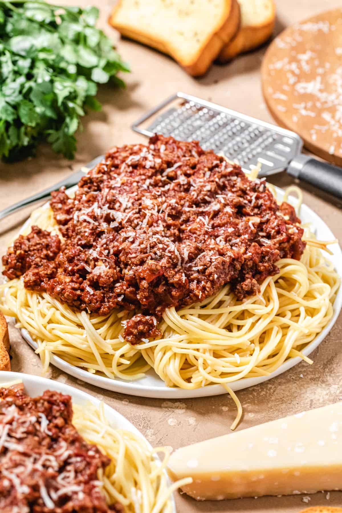 plate of spaghetti and meat sauce with fresh parmesan wedge in front