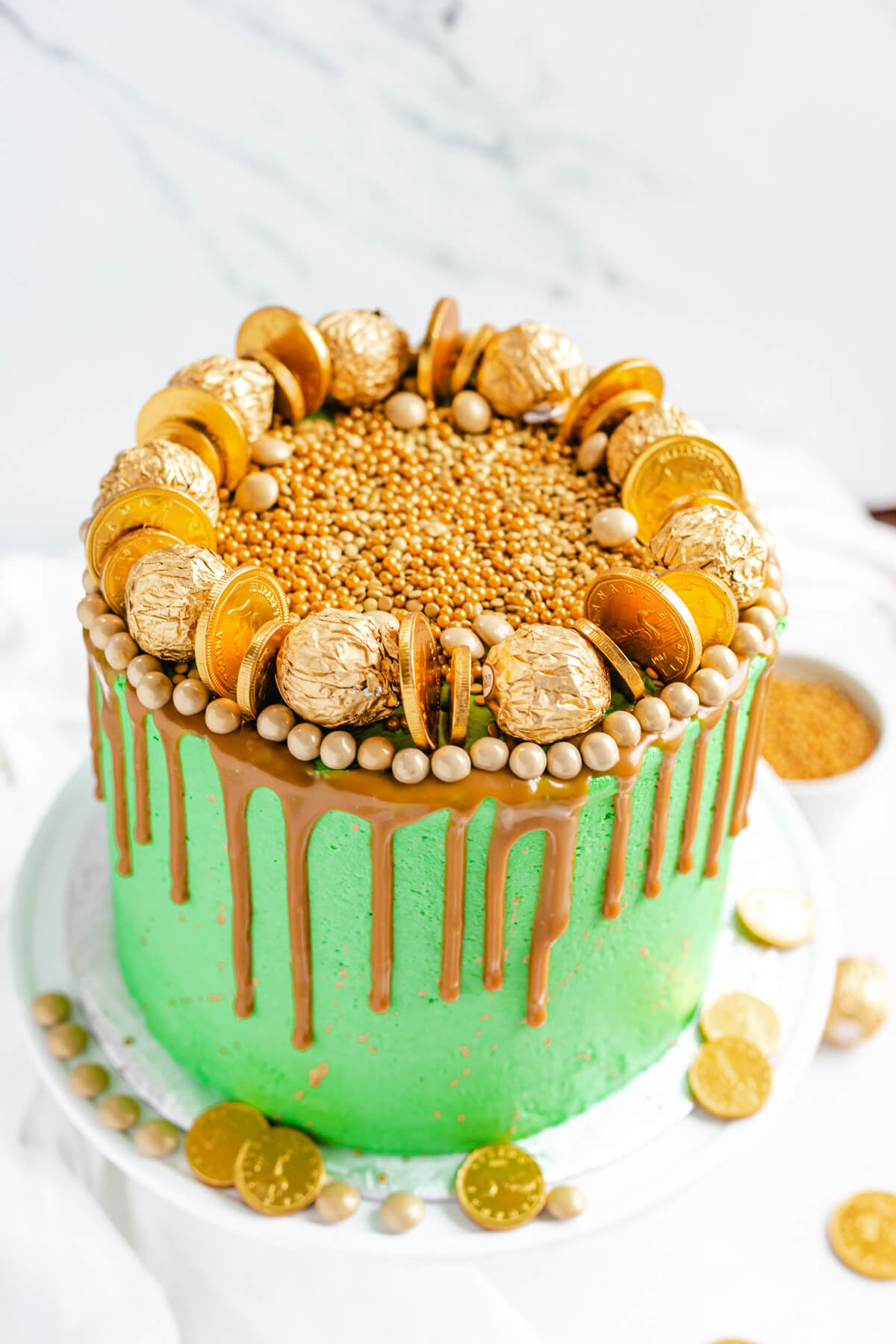 cake covered in gold candies on a white cake stand