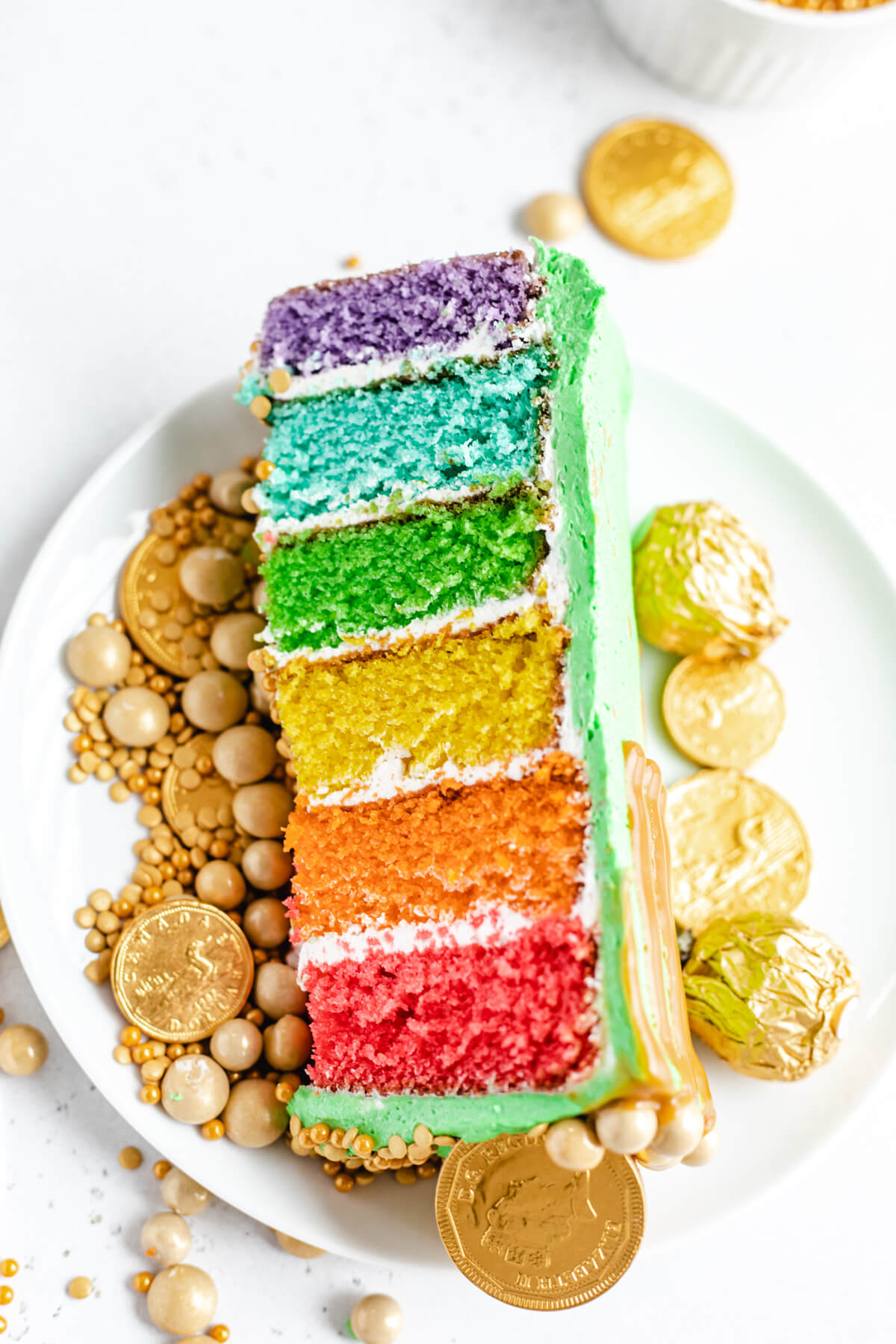 slice of cake on a white plate surrounded by gold candies