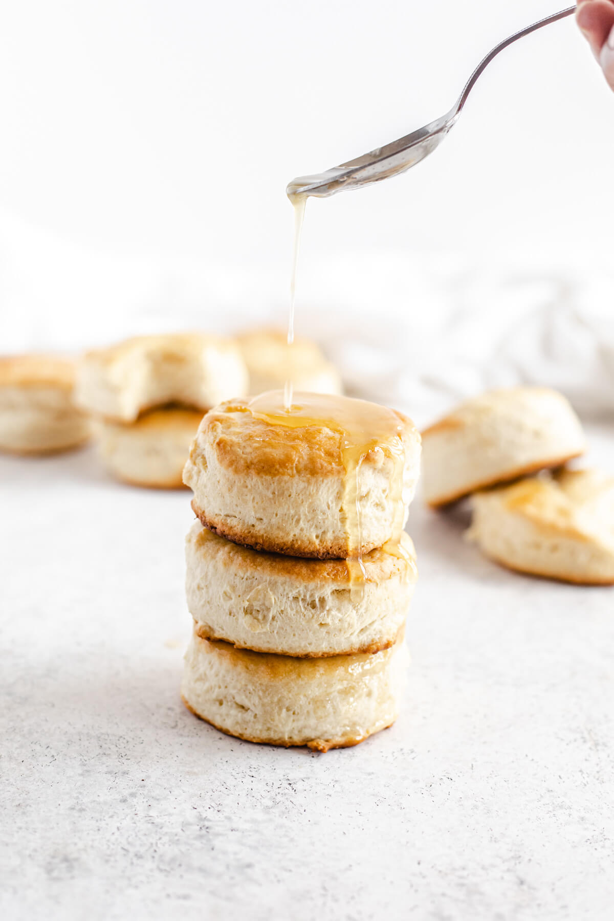 spooning honey butter glaze over biscuits