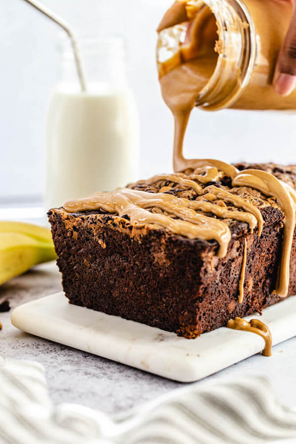 pouring melted peanut butter onto chocolate flavoured banana bread loaf