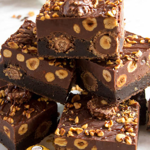 These Ferrero Rocher Fudge Brownies are the ultimate dessert bars! A Ferrero Rocher stuffed fudge brownie, topped with a creamy Nutella Fudge filled and topped with Ferrero Rochers and roasted hazelnuts. Take these bars to another level with a drizzle of silky Nutella Ganache and you’ve got the greatest brownie ever!  