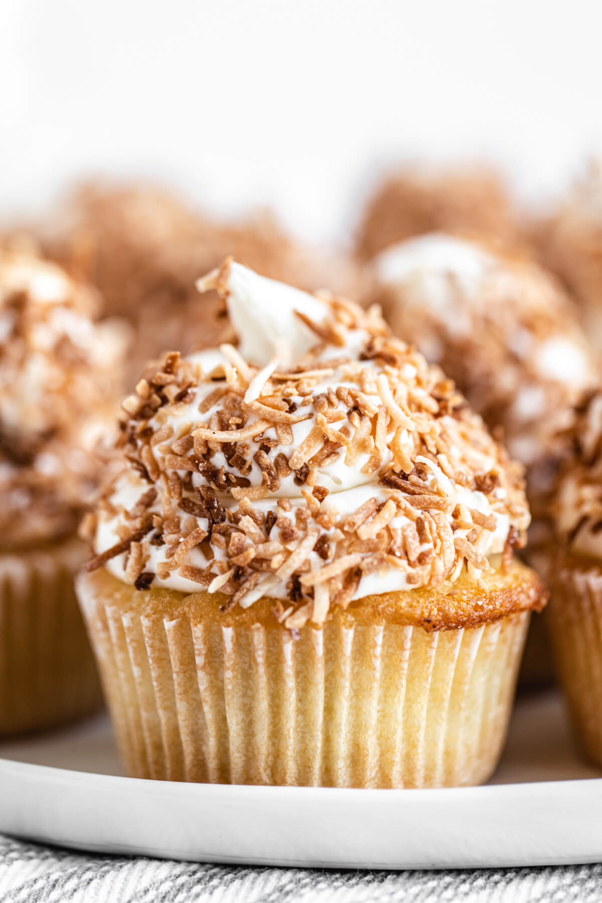 close up of coconut coated cupcake on a white serving platter