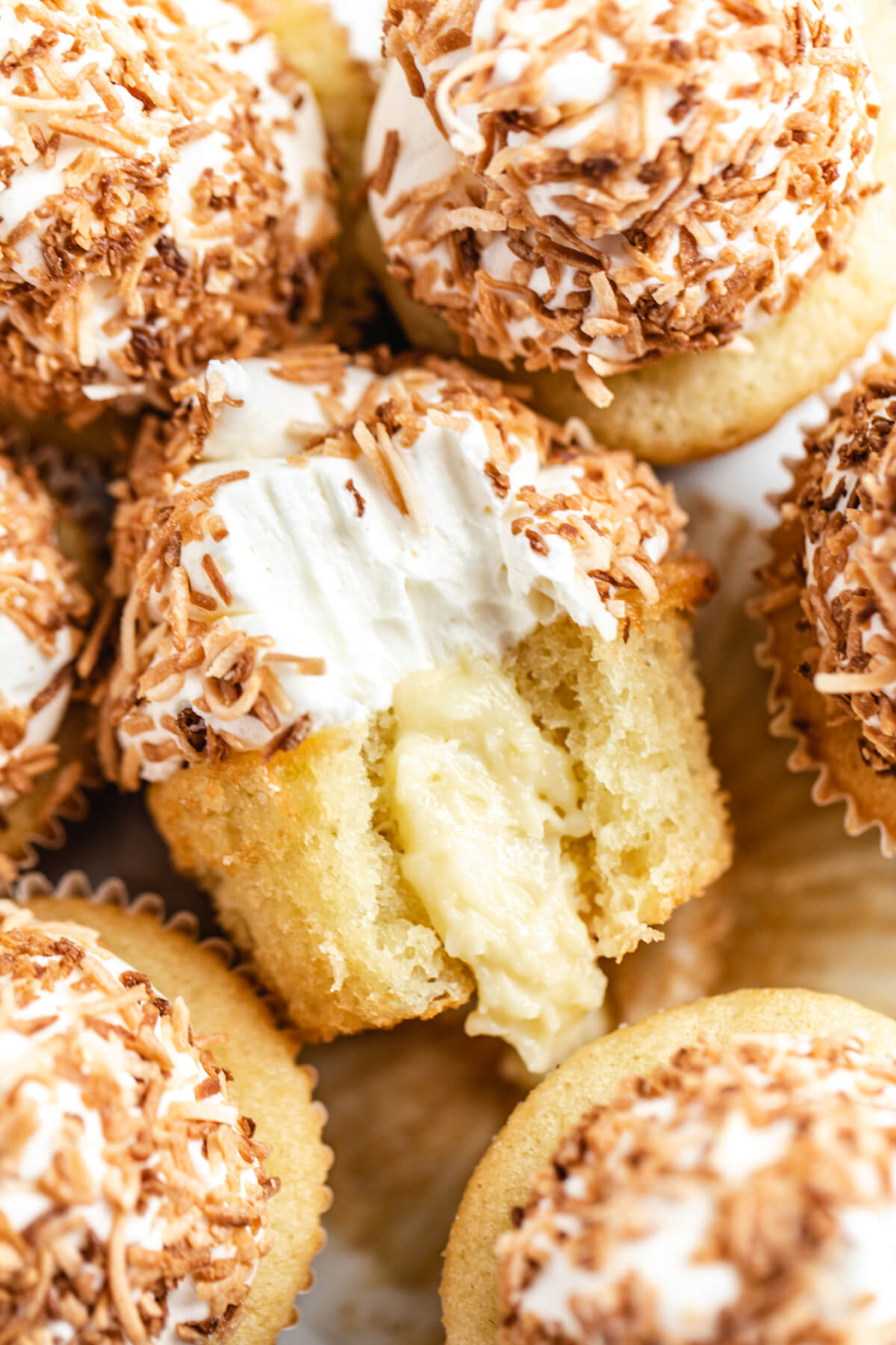 close up of cupcake with bite taken out and coconut custard spilling out