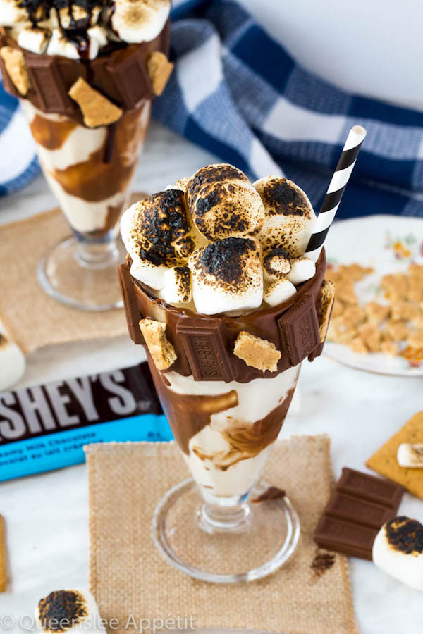 Give me S’mores Milkshake — milk chocolate and graham cracker decorated glass filled with a toasted marshmallow milkshake and topped with charred marshmallows! 