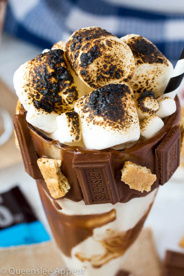 Give me S’mores Milkshake — milk chocolate and graham cracker decorated glass filled with a toasted marshmallow milkshake and topped with charred marshmallows! 