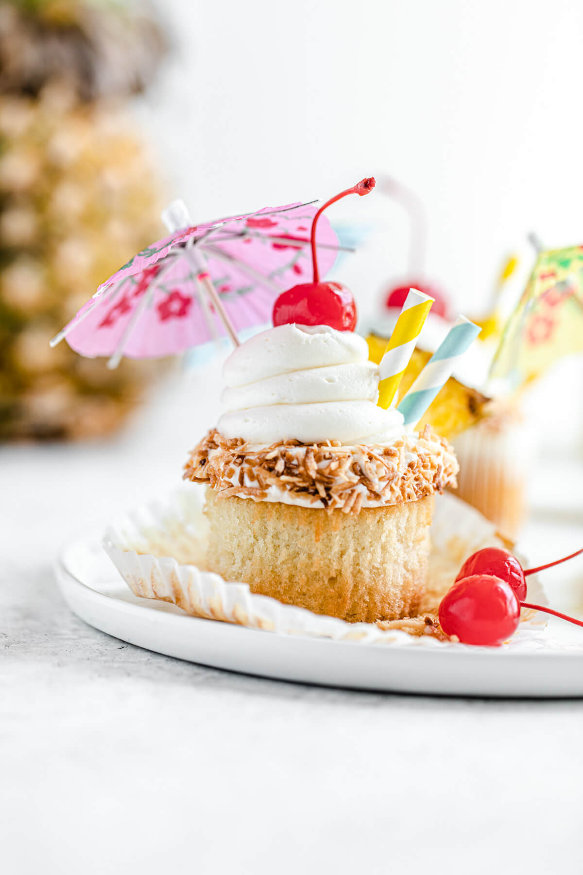 unwrapped cupcake on a white plate with pineapple in the background