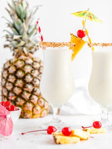 two glasses of milkshake with a pineapple in the background