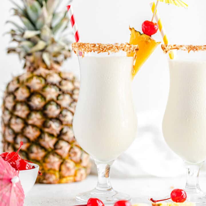two glasses of milkshake with a pineapple in the background