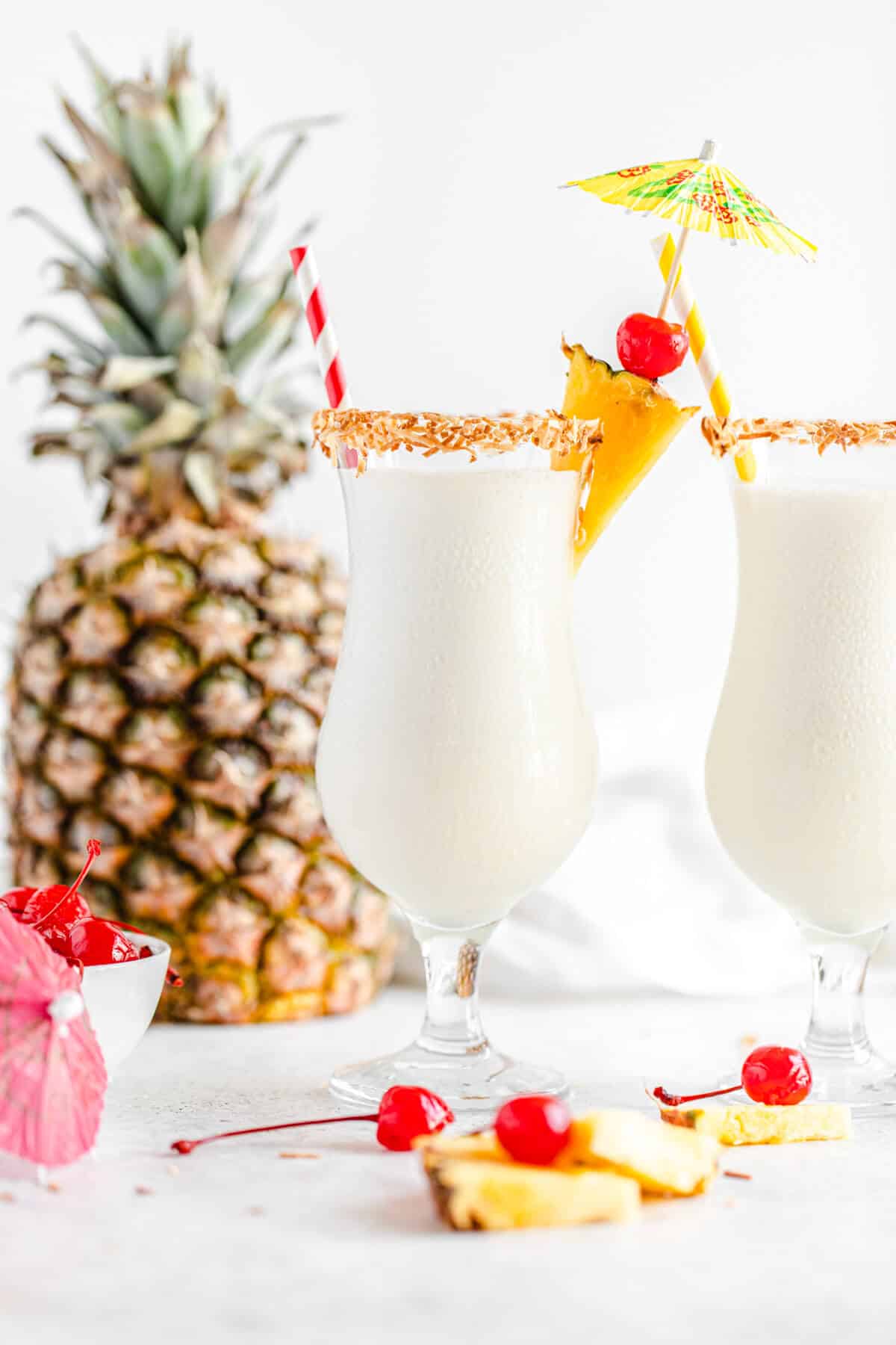 two glasses of milkshake with a pineapple in the background