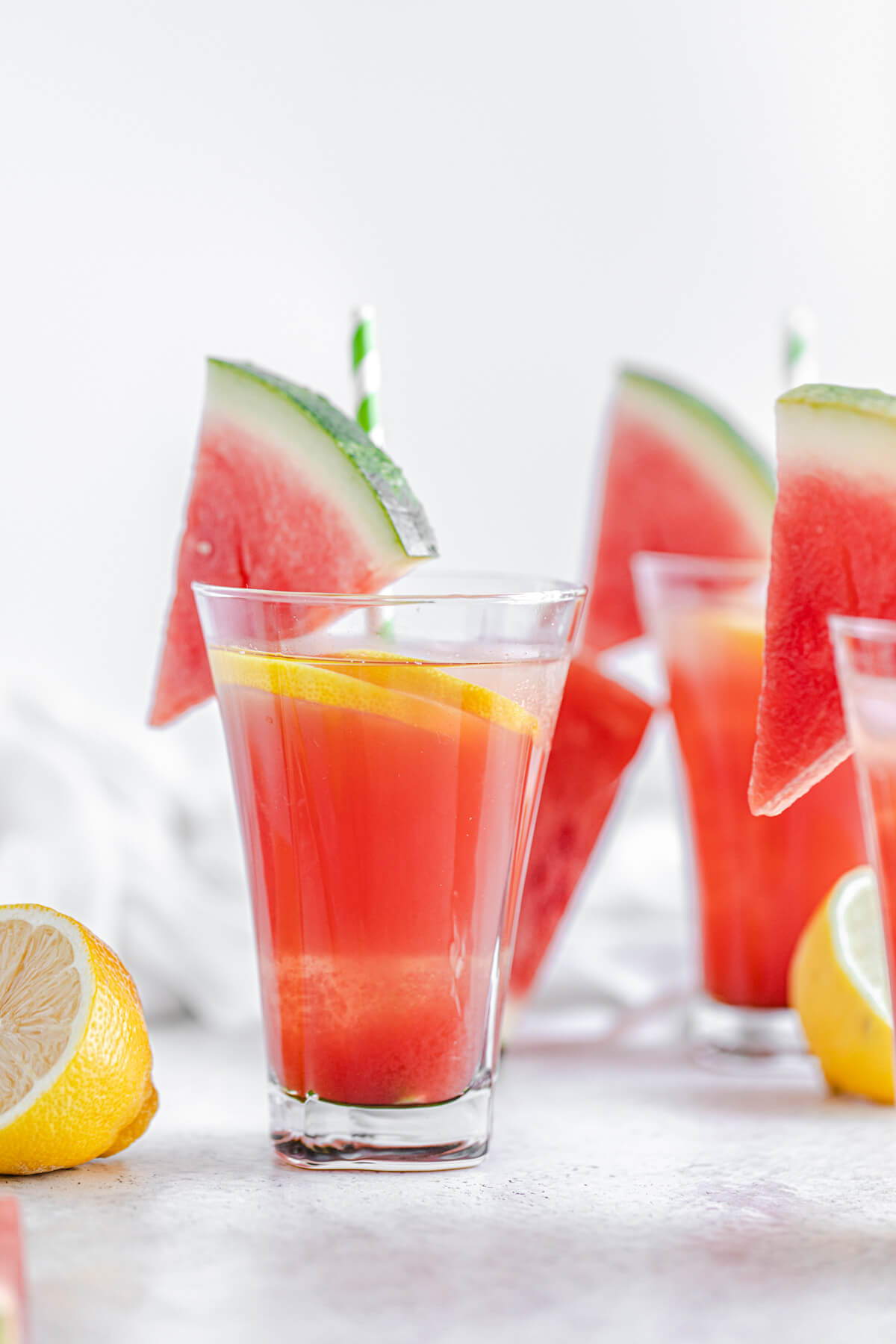 one glass of lemonade in the foreground with two glasses in the background