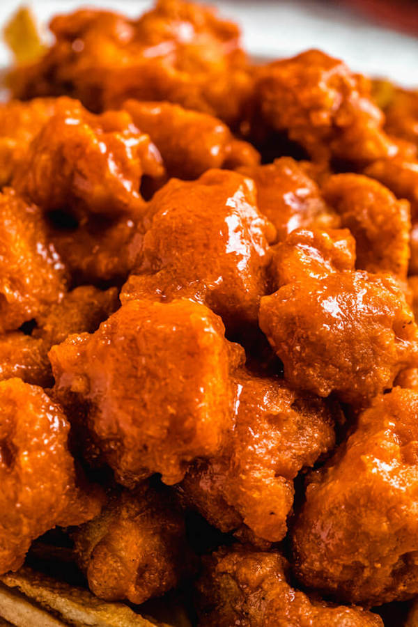 close up of buffalo sauce coated chicken pieces