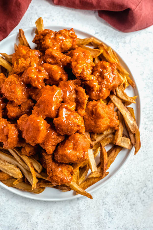 boneless buffalo chicken bites on top of crispy fries