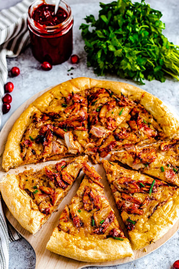 slices of cranberry bbq turkey pizza on a pizza stone