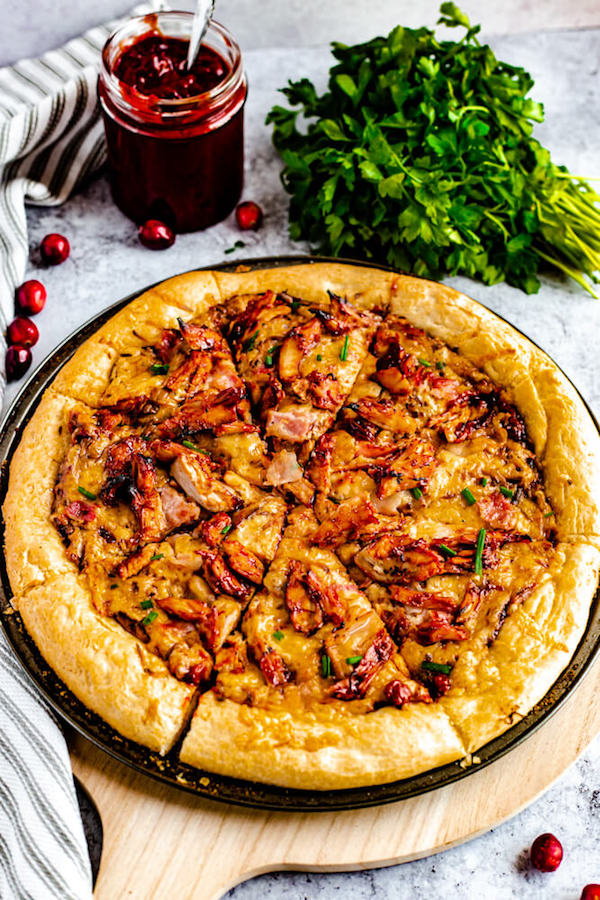 slices of cranberry bbq turkey pizza on a pizza stone