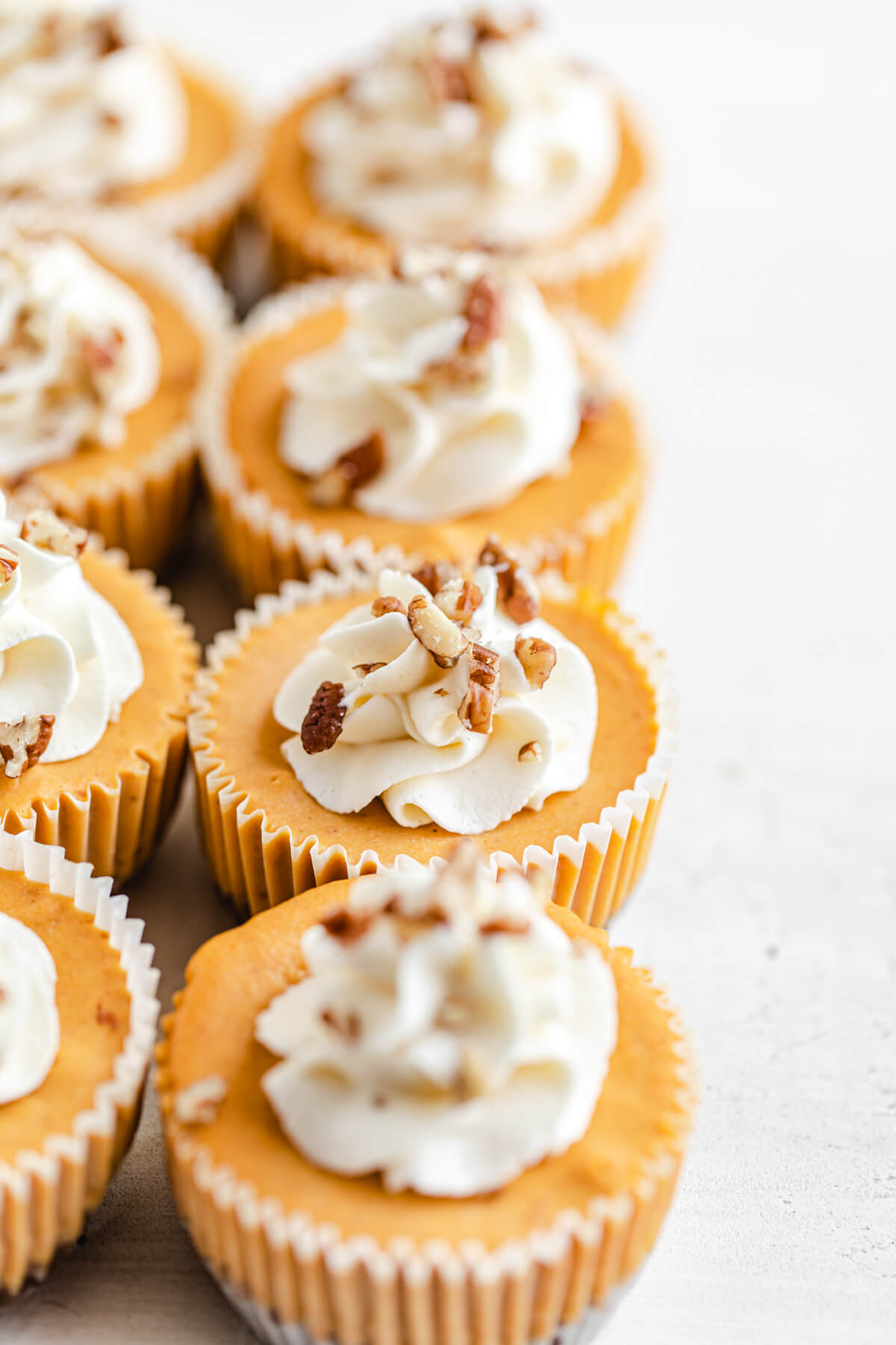 row of mini cheesecakes with whipped cream on top