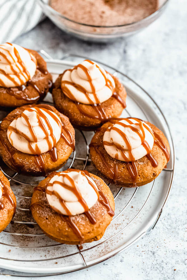 pumpkin donuts topped with salted caramel cream cheese frosting and salted caramel sauce drizzle on a round wire rack