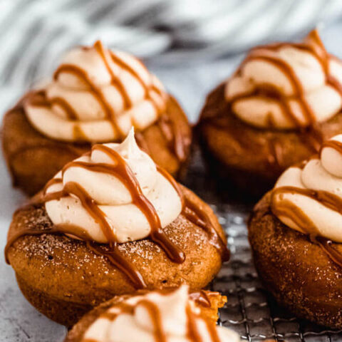 pumpkin donuts topped with salted caramel cream cheese frosting and salted caramel sauce drizzle on a safety grater