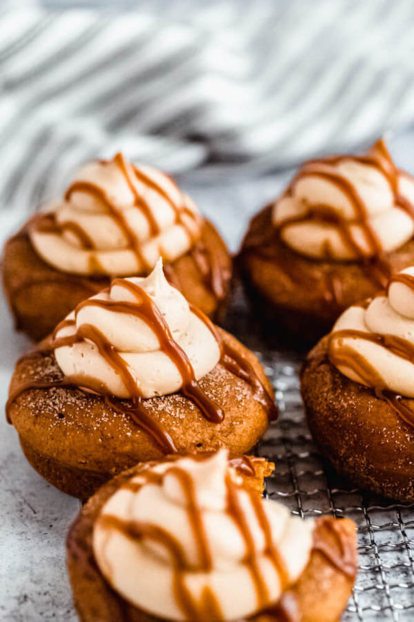 pumpkin donuts topped with salted caramel cream cheese frosting and salted caramel sauce drizzle on a safety grater