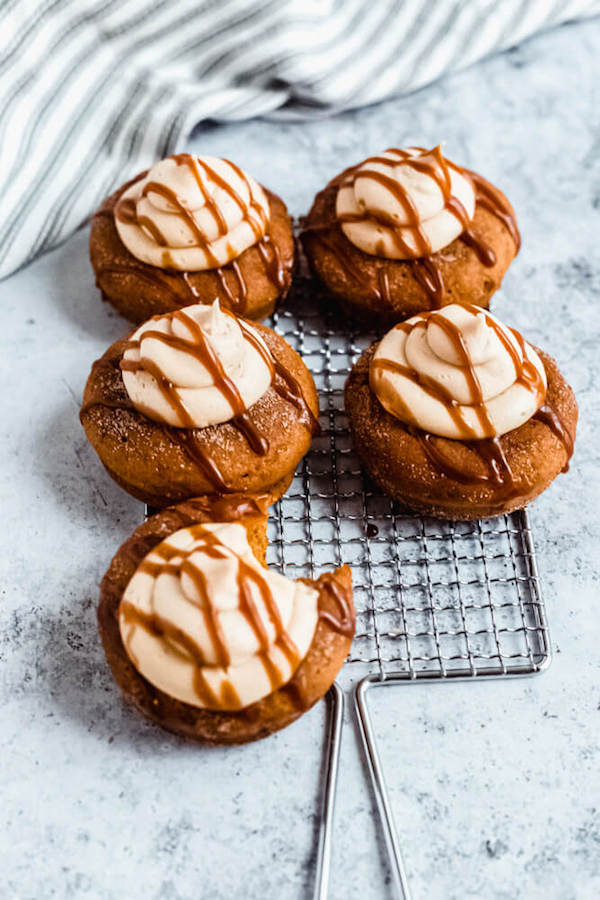 pumpkin donuts topped with salted caramel cream cheese frosting and salted caramel sauce drizzle on a safety grater