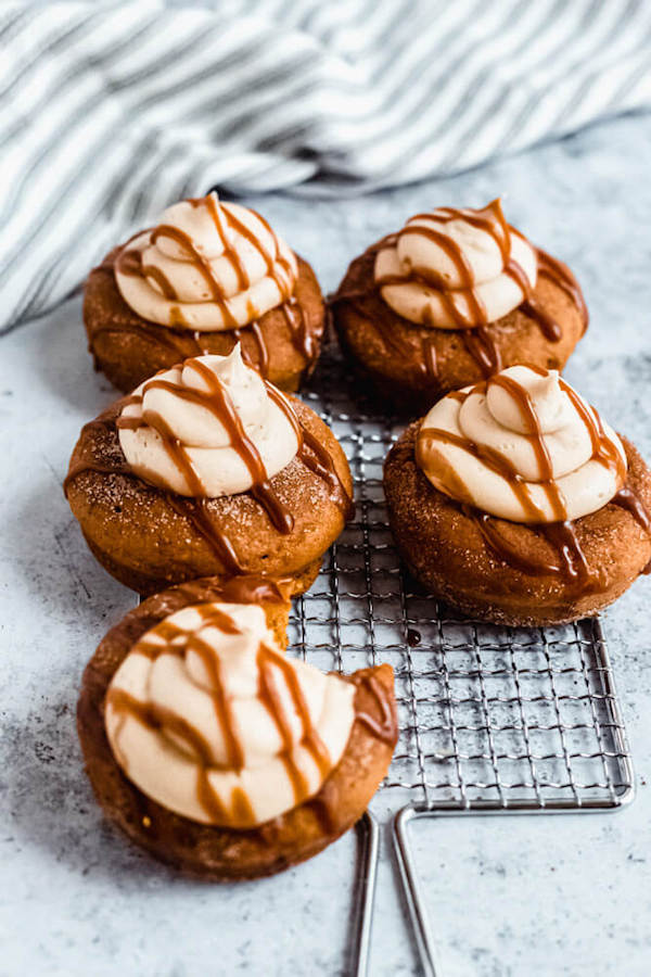 pumpkin donuts topped with salted caramel cream cheese frosting and salted caramel sauce drizzle on a safety grater