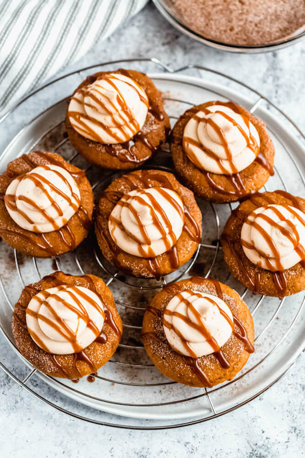 pumpkin donuts topped with salted caramel cream cheese frosting and salted caramel sauce drizzle on a round wire rack