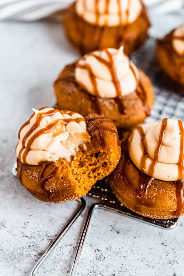 pumpkin donuts topped with salted caramel cream cheese frosting and salted caramel sauce drizzle on a round wire rack