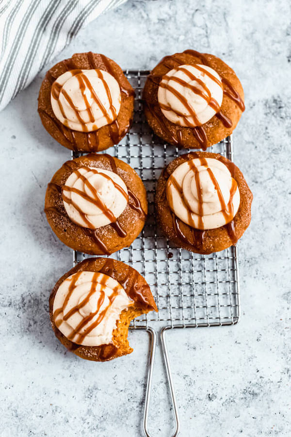 pumpkin donuts topped with salted caramel cream cheese frosting and salted caramel sauce drizzle on a safety grater