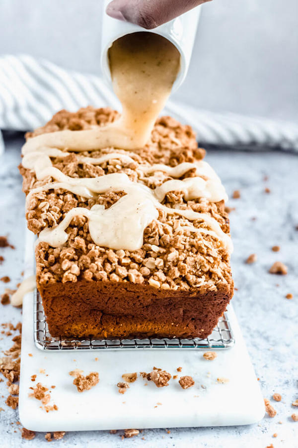 pouring browned butter cream cheese icing onto pumpkin streusel bread