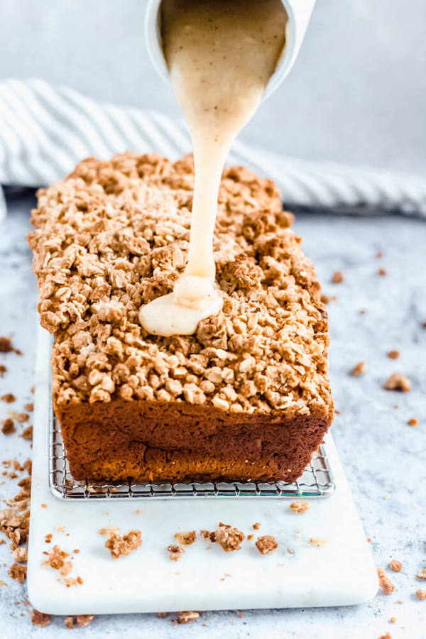 pouring browned butter cream cheese icing onto pumpkin streusel bread