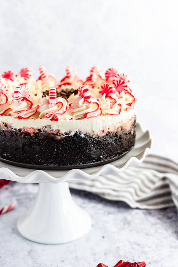 side view of white chocolate peppermint cheesecake on white cake stand