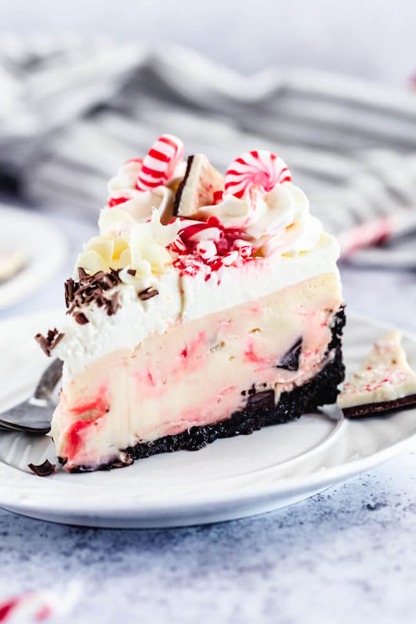 slice of candy cane bark cheesecake on white plate with fork