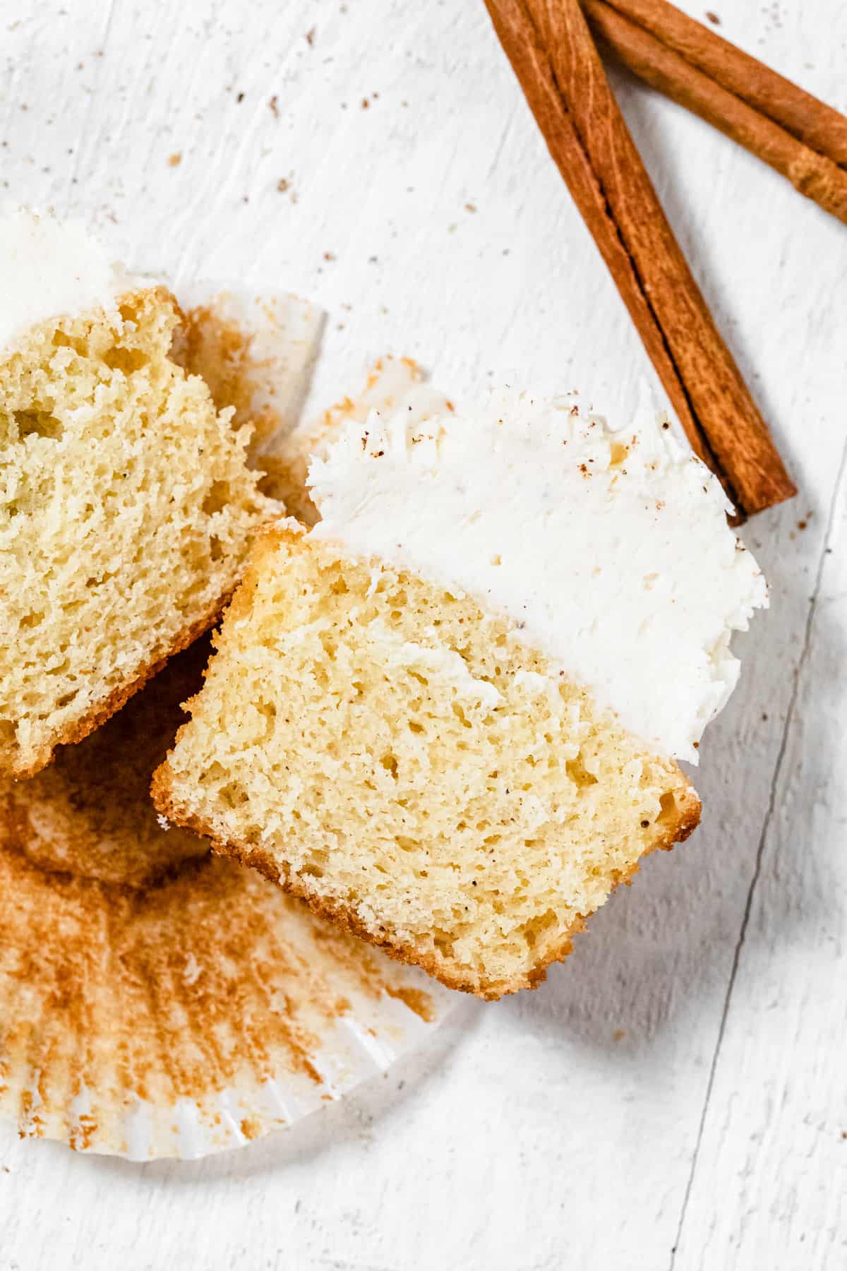 halved cupcakes on a cupcake liner with two cinnamon sticks above them